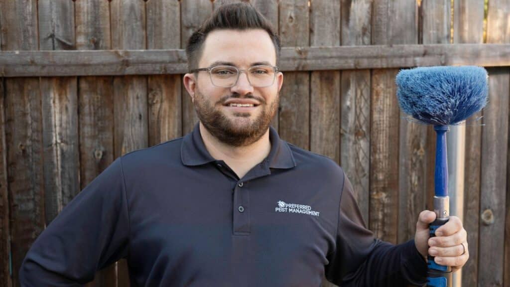 pest control technician standing with a wesbter duster in the backyard of a home in plano, tx