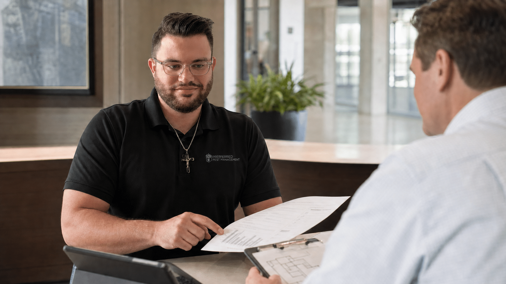 Preferred Pest Management technician reviewing a commercial pest inspection report with a property manager